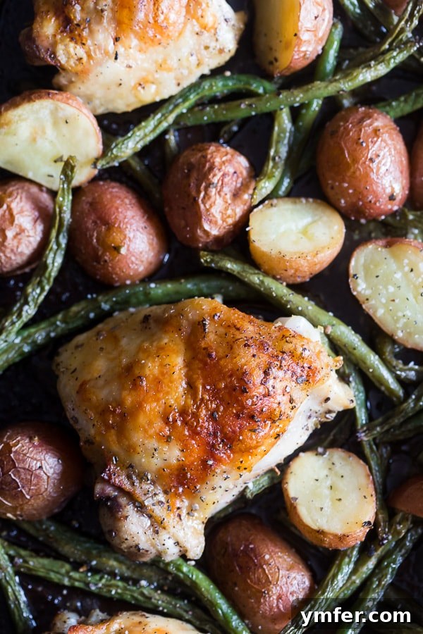 One-Pan Roasted Chicken and Potatoes 4 Close-up of golden brown chicken, tender potatoes, and roasted green beans on a sheet pan.