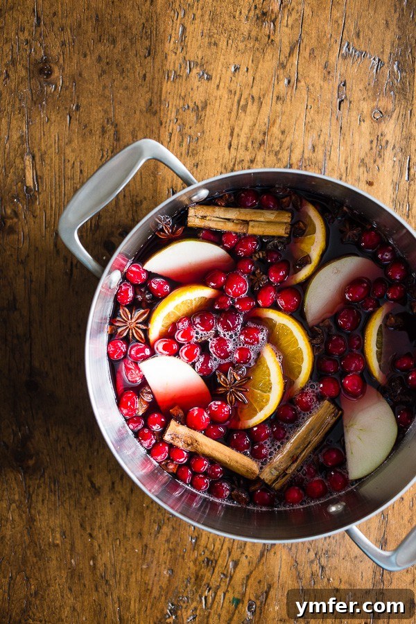 Spiced Winter Comfort 2 A large pot of Holiday Spiced Mulled Wine garnished with orange slices and cinnamon sticks, ready to be served.