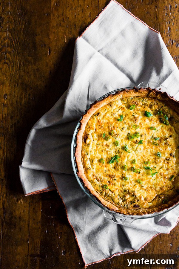 Rustic Bacon Onion Herb Quiche 4 A whole Bacon Onion Herb Quiche on a rustic wooden table with a slice removed.