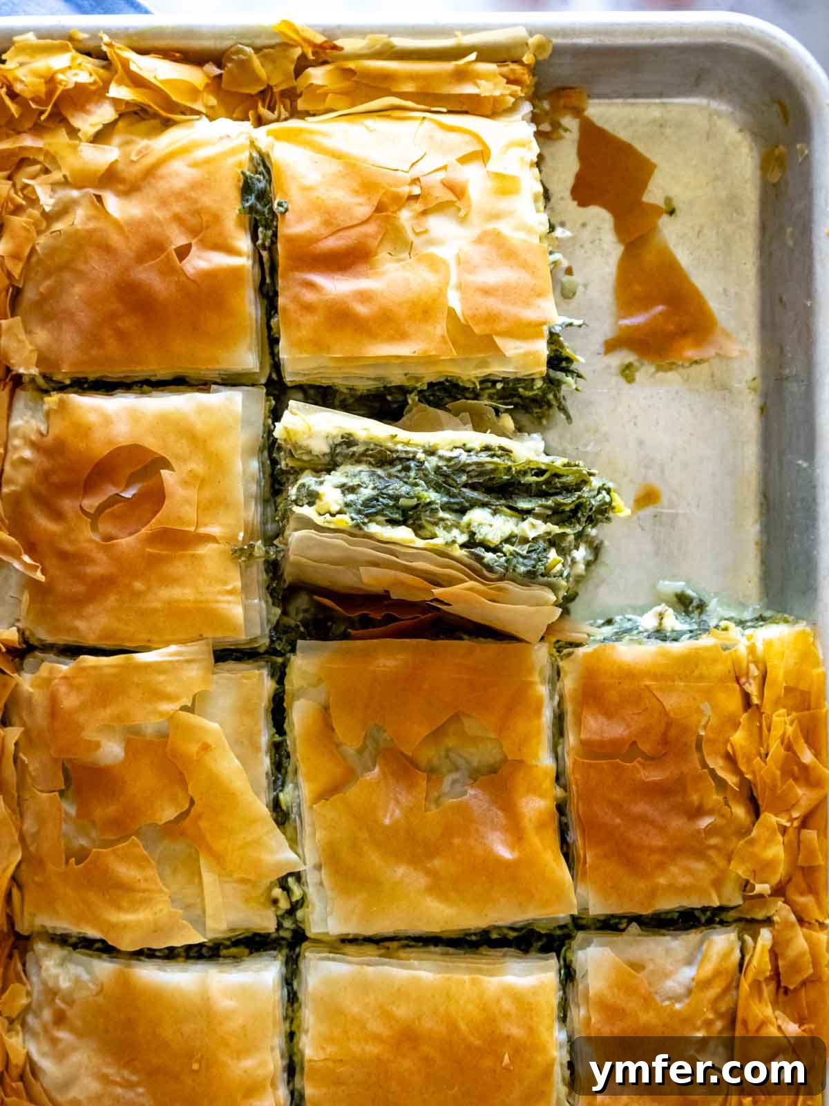 Flaky Greek Spinach and Feta Pie 2 Freshly baked Spanakopita glistening on a baking tray, showcasing its golden, crispy phyllo crust.