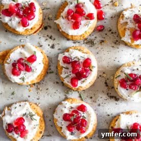 A plate of festive Whipped Goat Cheese Bites, adorned with pomegranate and rosemary.