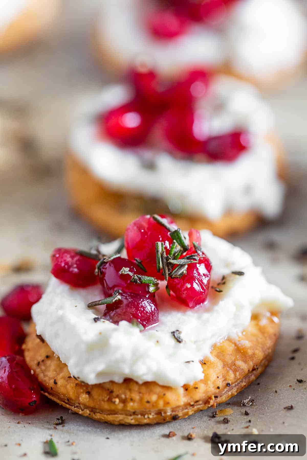 Tangy Chevre Clouds 6 Whipped Goat Cheese Bites garnished with fresh pomegranate seeds and sprigs of rosemary, ready to be served on a platter.