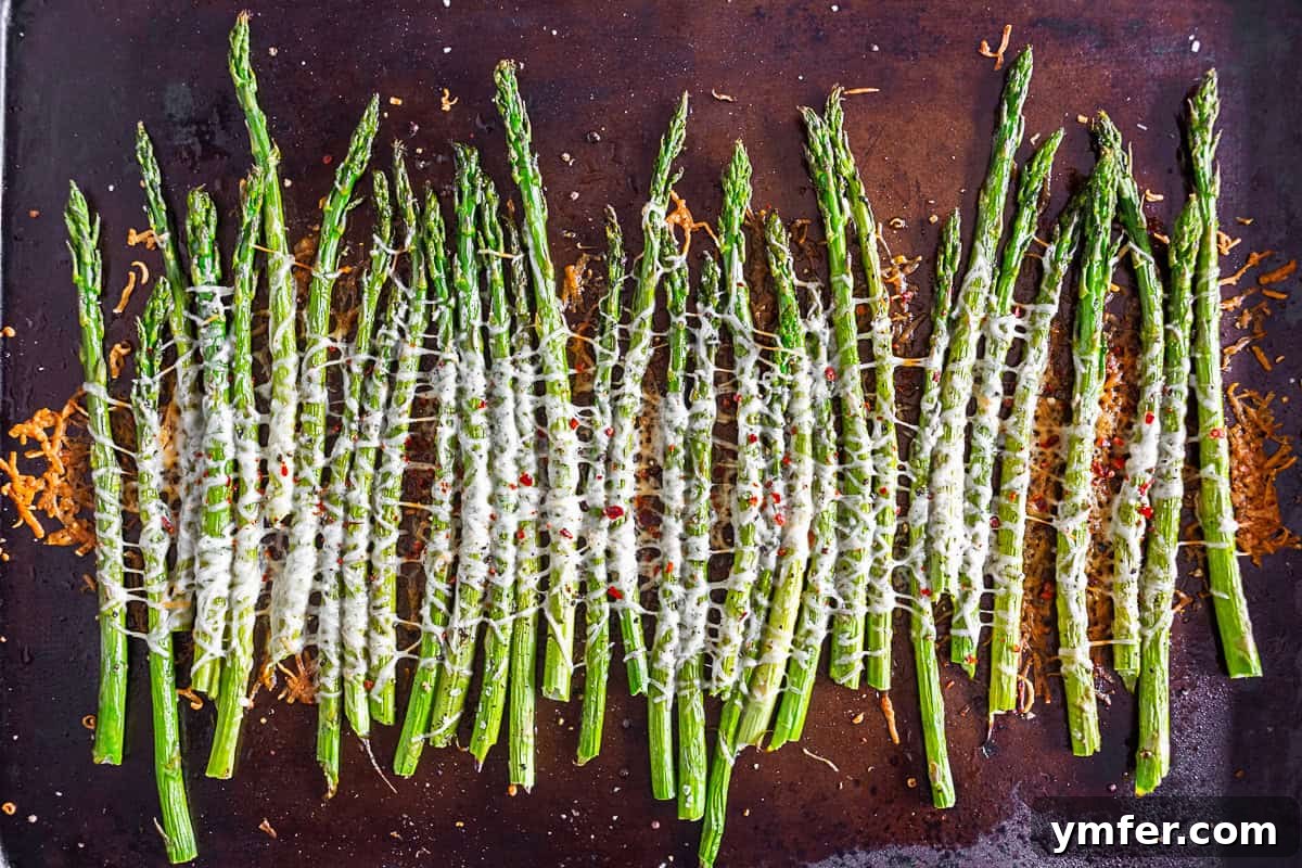 Crispy Parmesan Roasted Asparagus 3 Close-up of Parmesan Roasted Asparagus topped with crushed red pepper, showing the melted cheese.