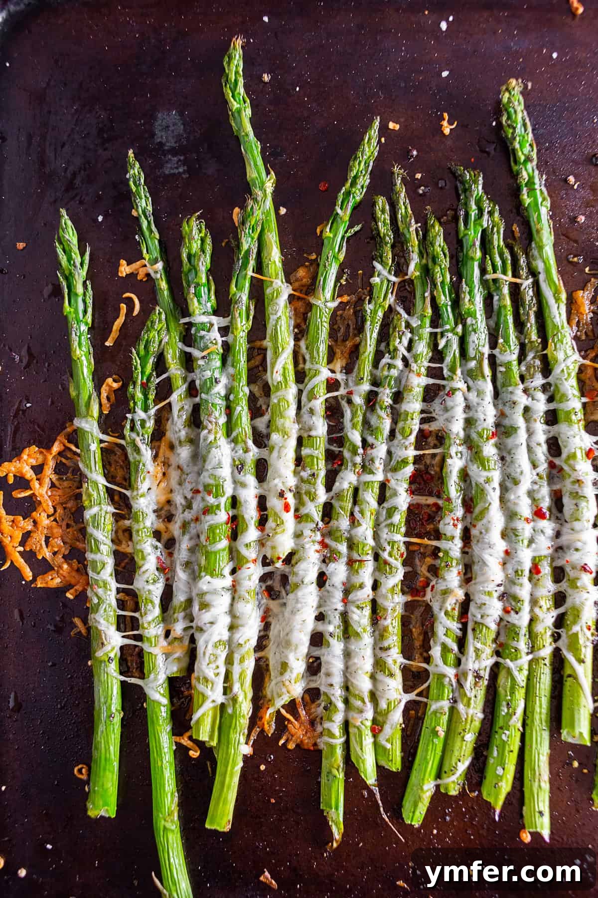 Crispy Parmesan Roasted Asparagus 5 Parmesan Roasted Asparagus on a baking sheet pan with fresh herbs, ready to be enjoyed.