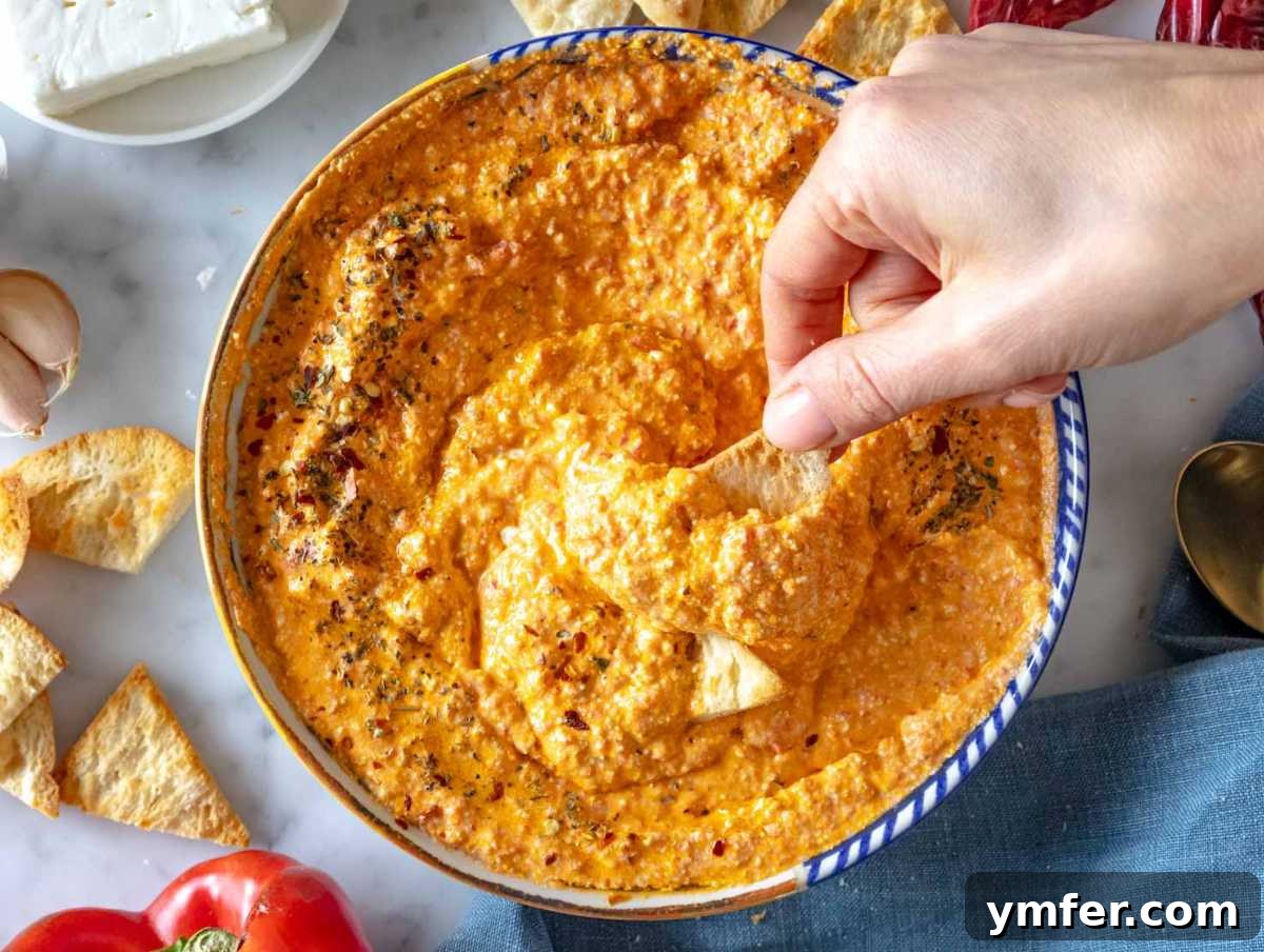 Fiery Feta Delight 3 A person dipping crispy pita chips into a bowl of homemade Tirokafteri.
