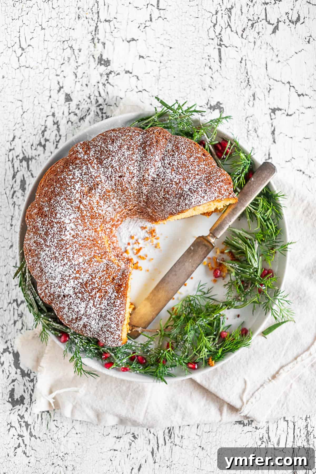 Elegant Sherry Bundt Cake 6 A whole cream sherry bundt cake presented on a decorative serving platter, accompanied by a serving knife, ready to be sliced and enjoyed.