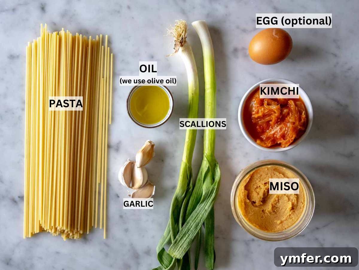 Umami Gold 3 Fresh ingredients for miso pasta, including bucatini, miso paste, kimchi, and garlic, arranged on a rustic kitchen countertop.