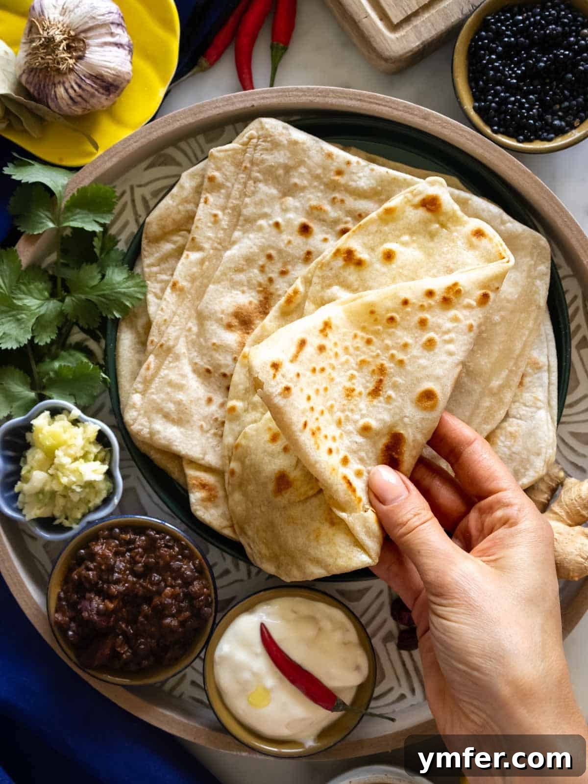 Flaky Stuffed Paratha Perfection 4 A close-up of hands expertly folding a soft and flaky paratha dough, highlighting its pliability.