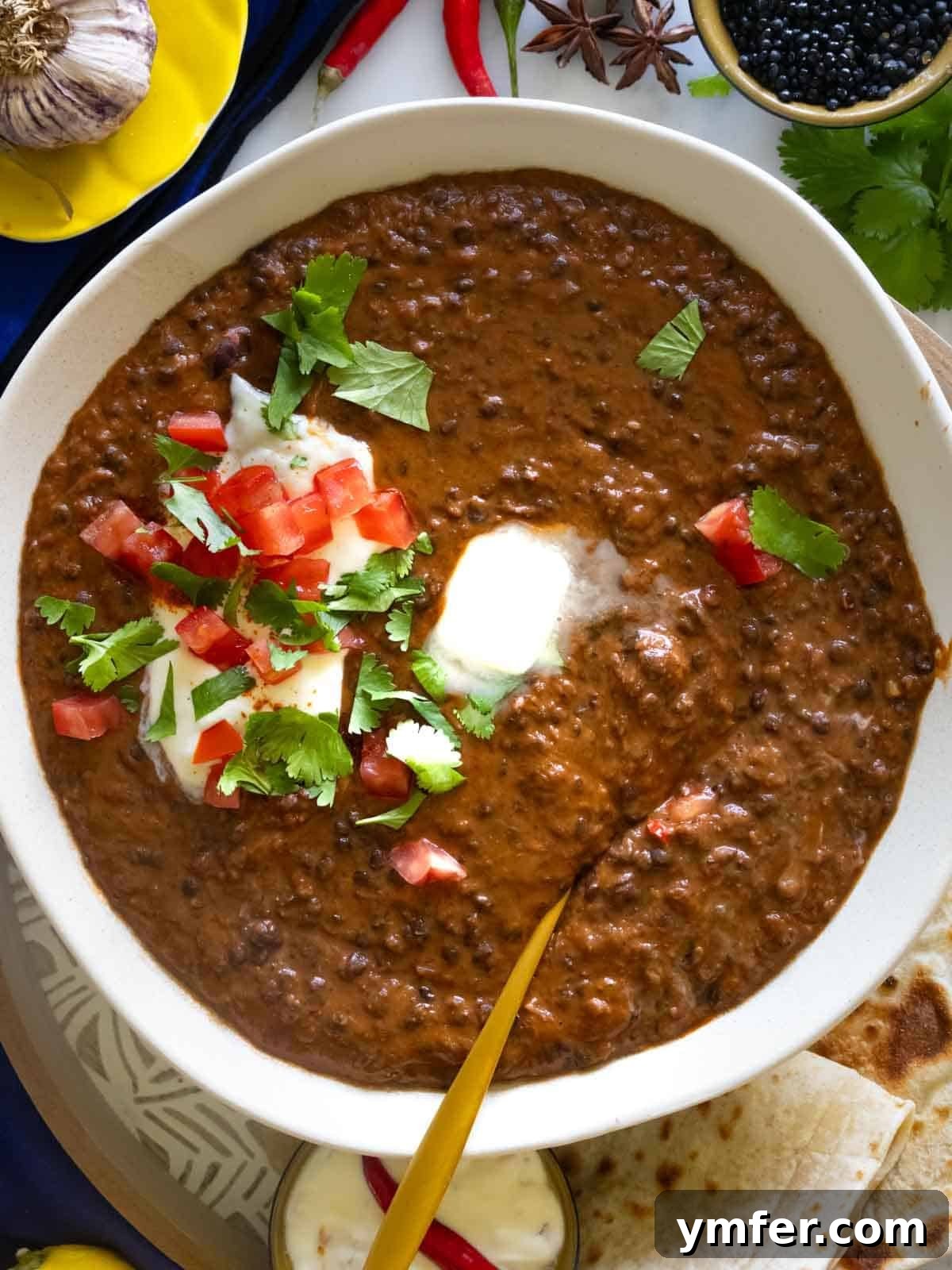 Dal Makhani Black Lentil Curry 5 A close-up shot of rich black lentil dal, garnished with fresh cilantro and a dollop of raita, ready to be served.