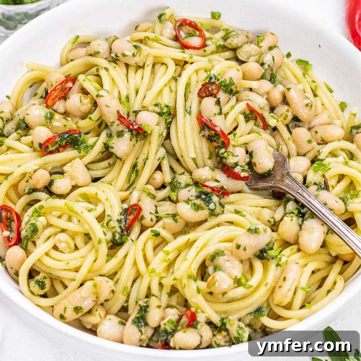 25 High Fiber Power Foods 24 aglio e olio with cannellini beans and a fork.