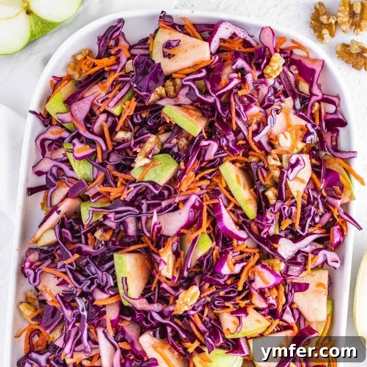 A vibrant no-mayo coleslaw with crisp green apple and rich red cabbage, presented on a serving platter.