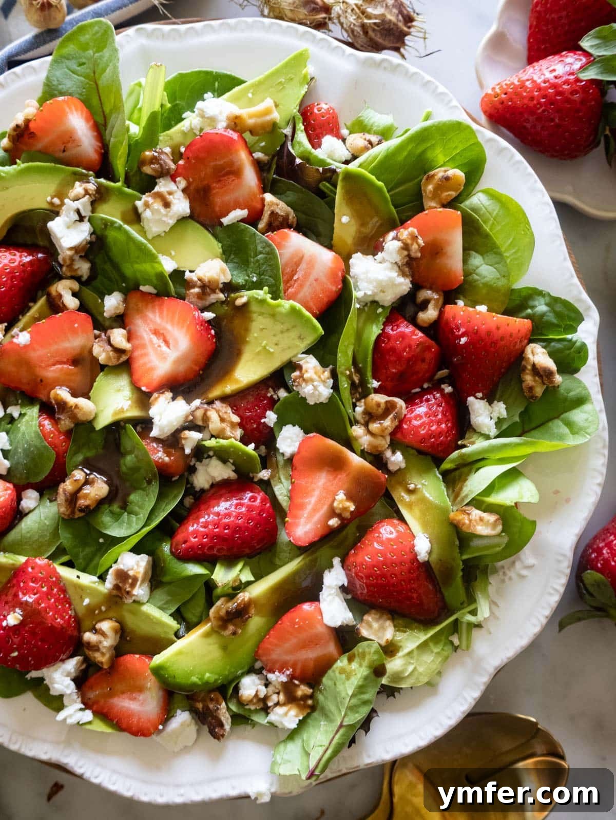 Vibrant Strawberry Spinach Salad 2 Vibrant Strawberry Spinach Salad on a white serving platter, garnished with fresh herbs.