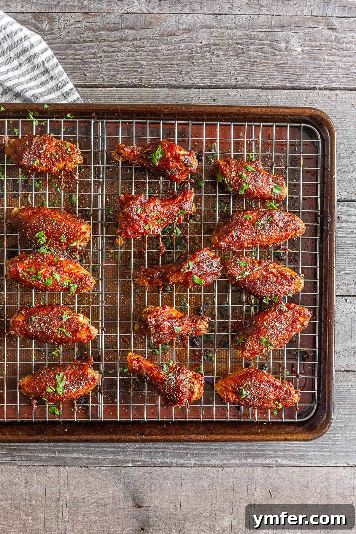 Sticky Apple Butter Wings 2 Perfectly baked apple butter chicken wings arranged neatly on a wire cooling rack over a grilling tray, showcasing their crispy skin and rich glaze.