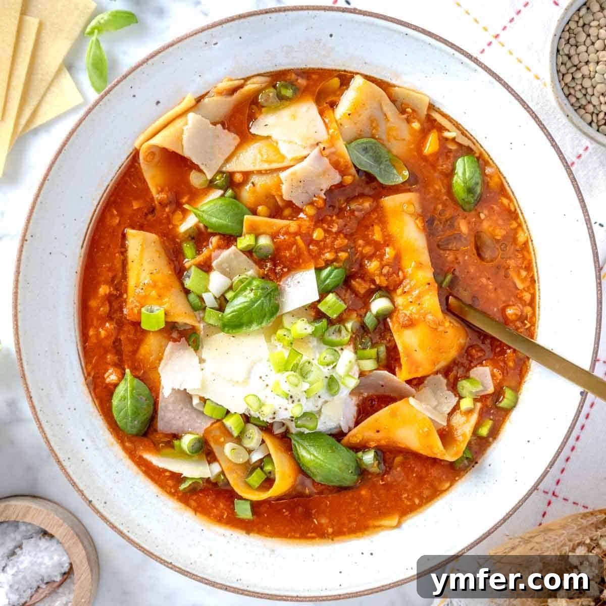 Heart-Smart Meals 22 lasagna soup with ricotta, basil leaves, and a golden spoon. A hearty and flavorful vegetarian soup.