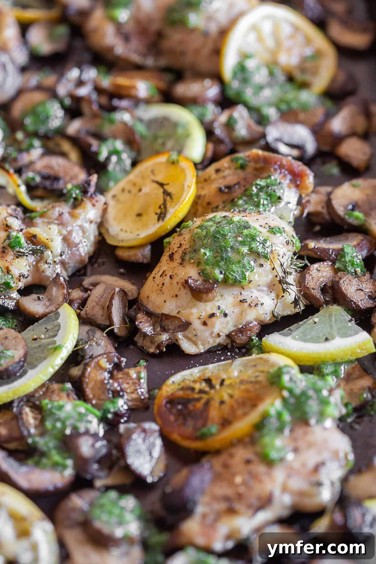 One Pan Zesty Lemon Garlic Chicken 5 Close-up of Sheet Pan Garlic Lemon Chicken and Mushrooms, garnished with fresh lemon wedges and parsley, highlighting the vibrant colors and appealing texture.