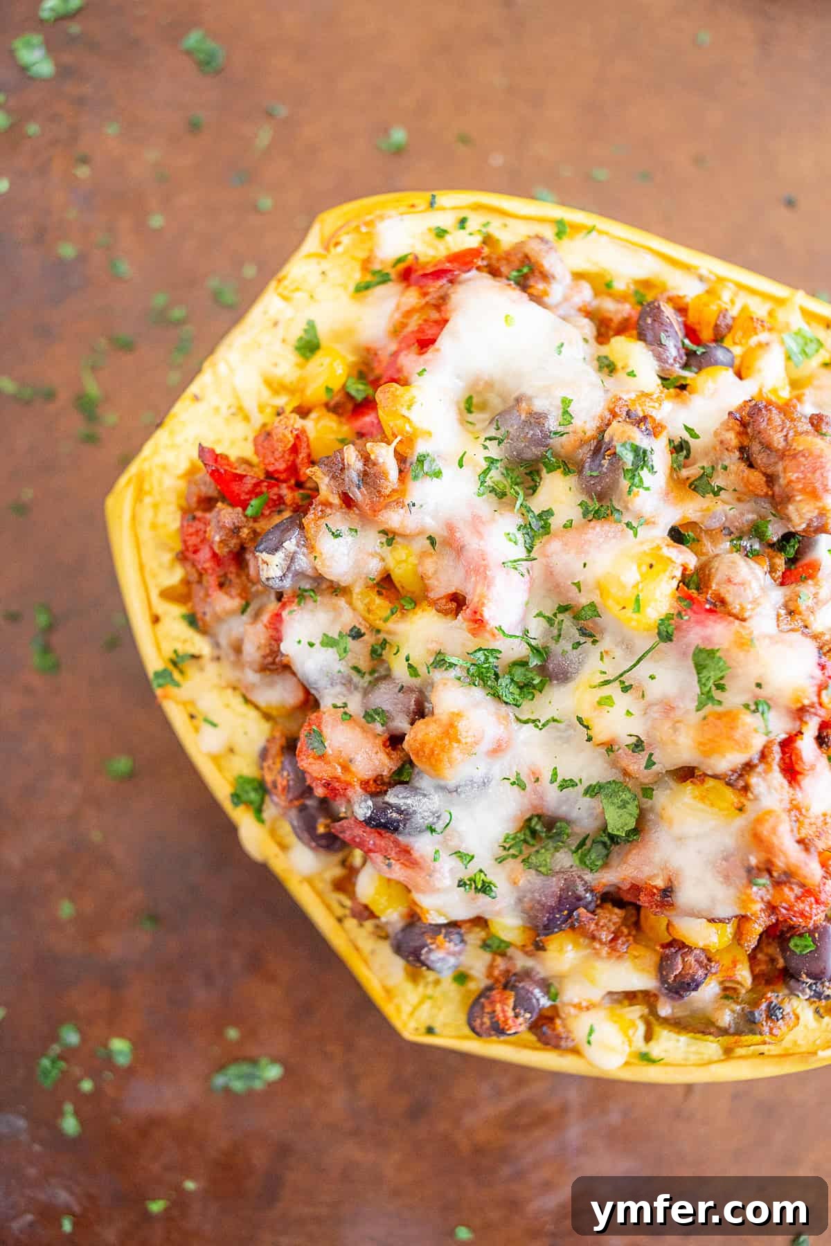 Zesty Southwest Taco Spaghetti Squash Boats 2 Two halves of Southwest taco stuffed spaghetti squash on a sheet pan, topped with melted cheese and fresh cilantro.