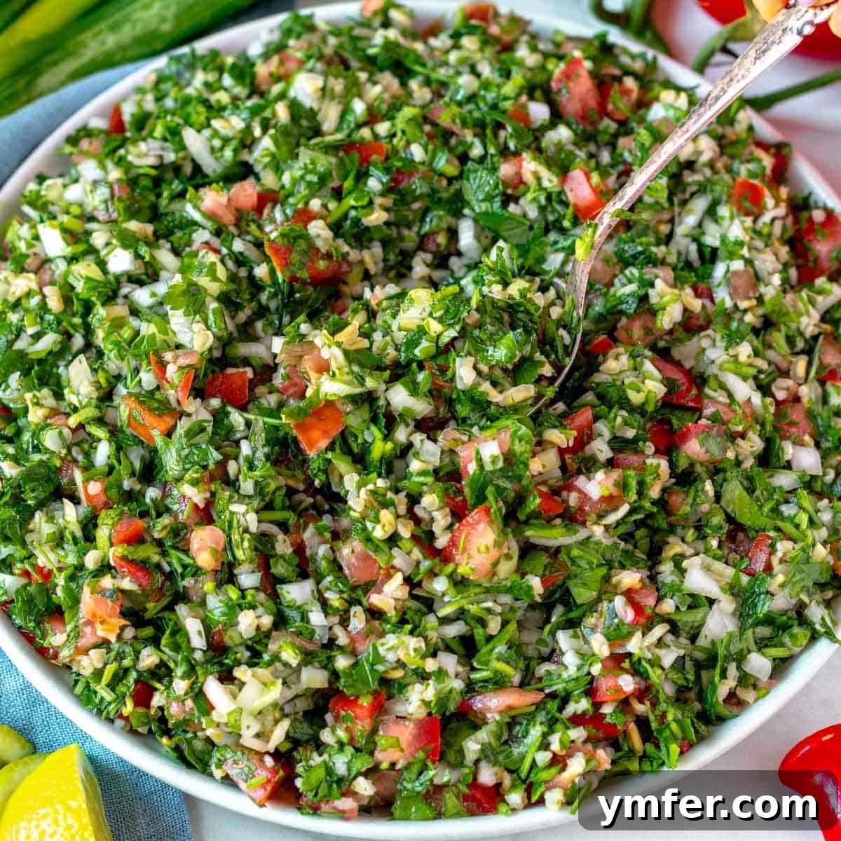 21 Fresh & Flavorful Summer Salads 22 Tabbouleh salad on a white plate with a silver spoon, garnished with lemon wedges.