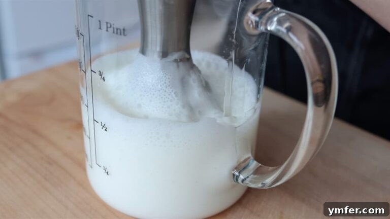 Slowly drizzling the oil in the tall container
