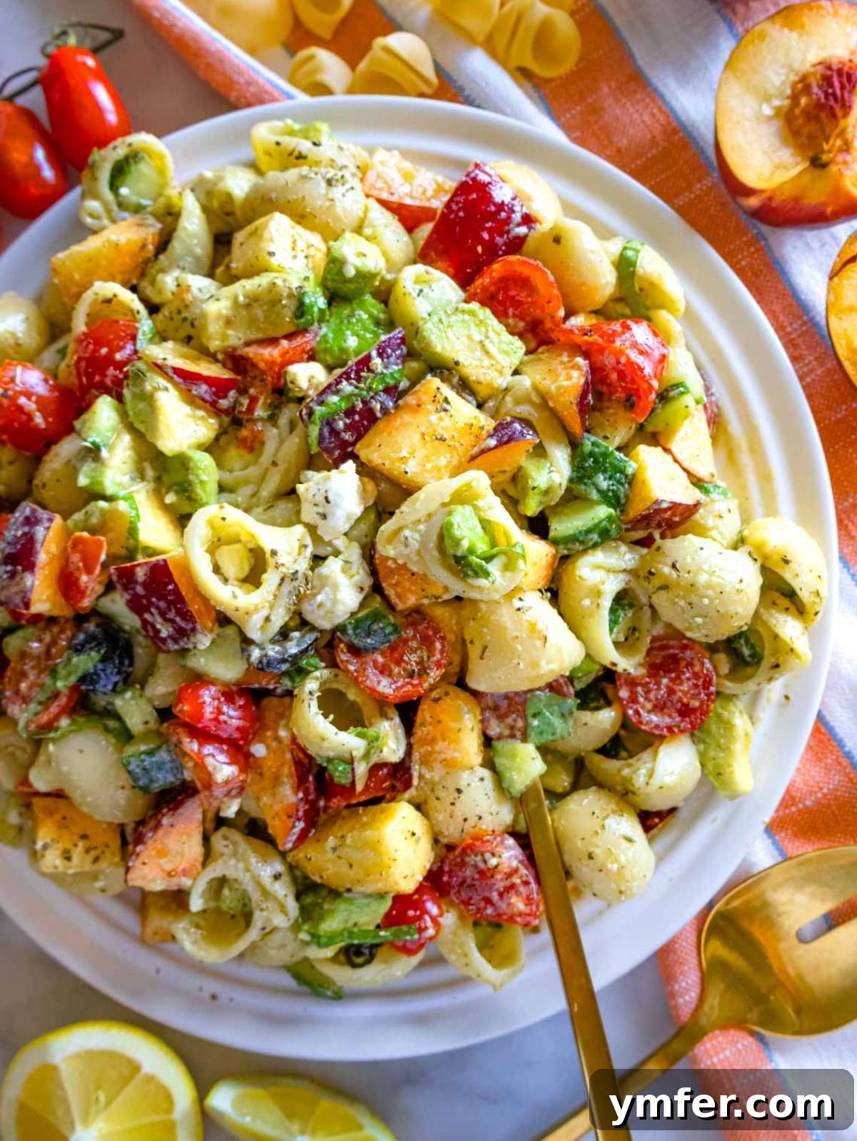 Summer Peach & Creamy Feta Delight 2 Summer pasta salad with peach served on a large white platter, garnished with basil, feta, and diced peaches, ready to serve.