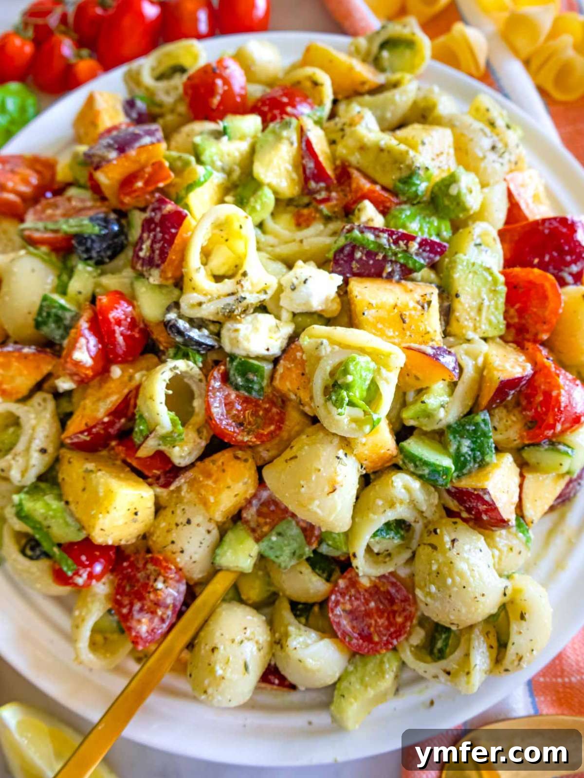 Summer Peach & Creamy Feta Delight 3 Close-up of summer pasta salad highlighting creamy avocado, juicy peaches, cherry tomatoes, and crumbled feta.