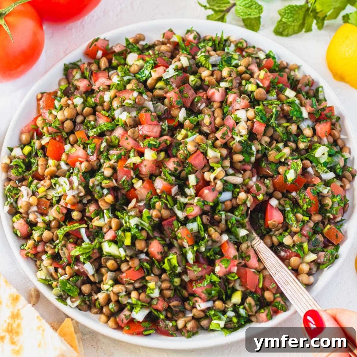 30 Delectable Picnic Recipes 11 Close-up of fresh lentil tabbouleh with a silver spoon, showing its vibrant herbs and textures.