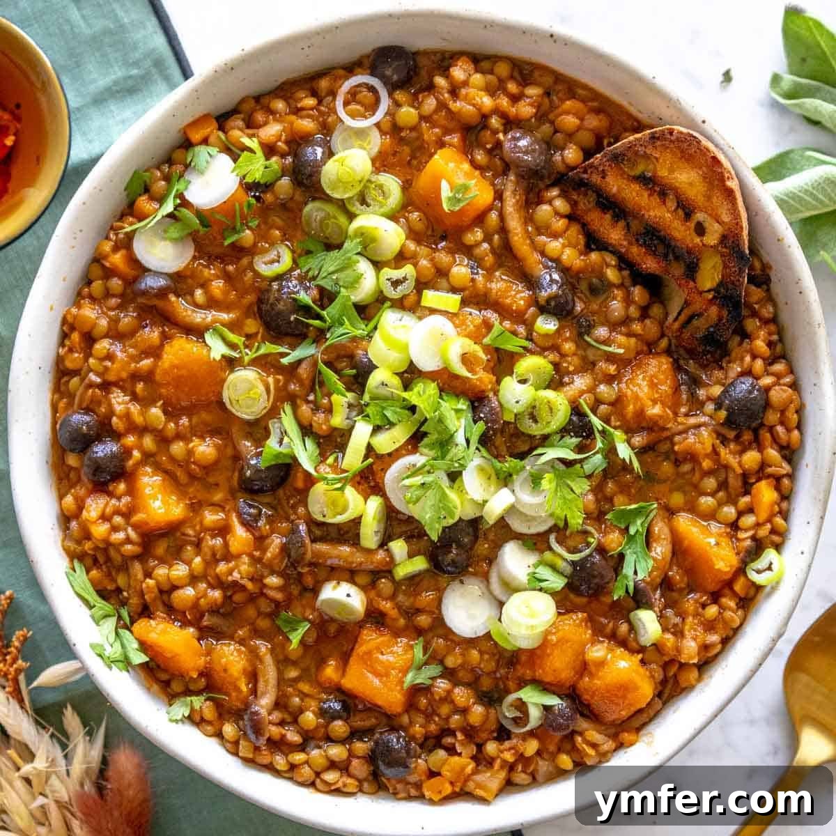 Mediterranean Diet for Vibrant Health 8 A rustic bowl of hearty lentil stew, garnished with fresh green scallions, served alongside a crusty slice of artisanal bread for dipping, offering a comforting and wholesome meal.
