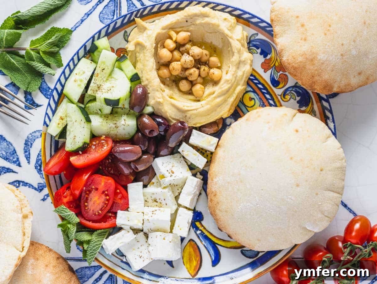 Mediterranean Diet for Vibrant Health 9 A vibrant mezze platter featuring a generous portion of creamy hummus, surrounded by crispy pita bread, assorted Kalamata olives, and colorful fresh vegetables like cucumber and bell peppers.