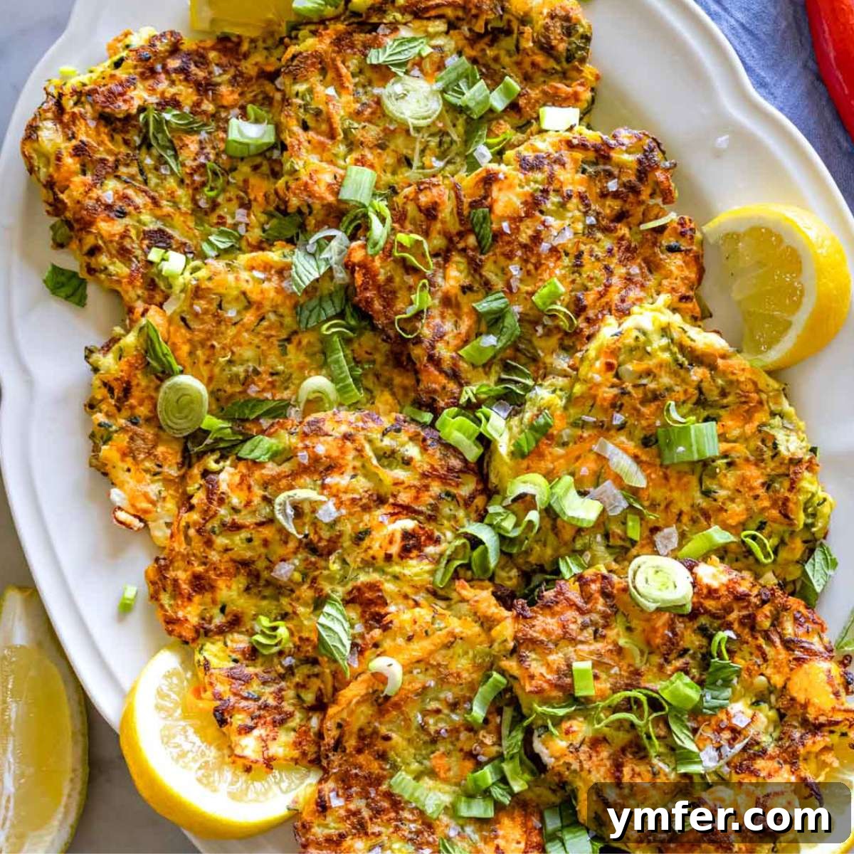 Mediterranean Diet for Vibrant Health 11 Healthy and delicious Greek zucchini patties, made with feta cheese, fresh herbs, and grated vegetables, elegantly served on a rustic plate with a dollop of creamy tzatziki yogurt sauce.