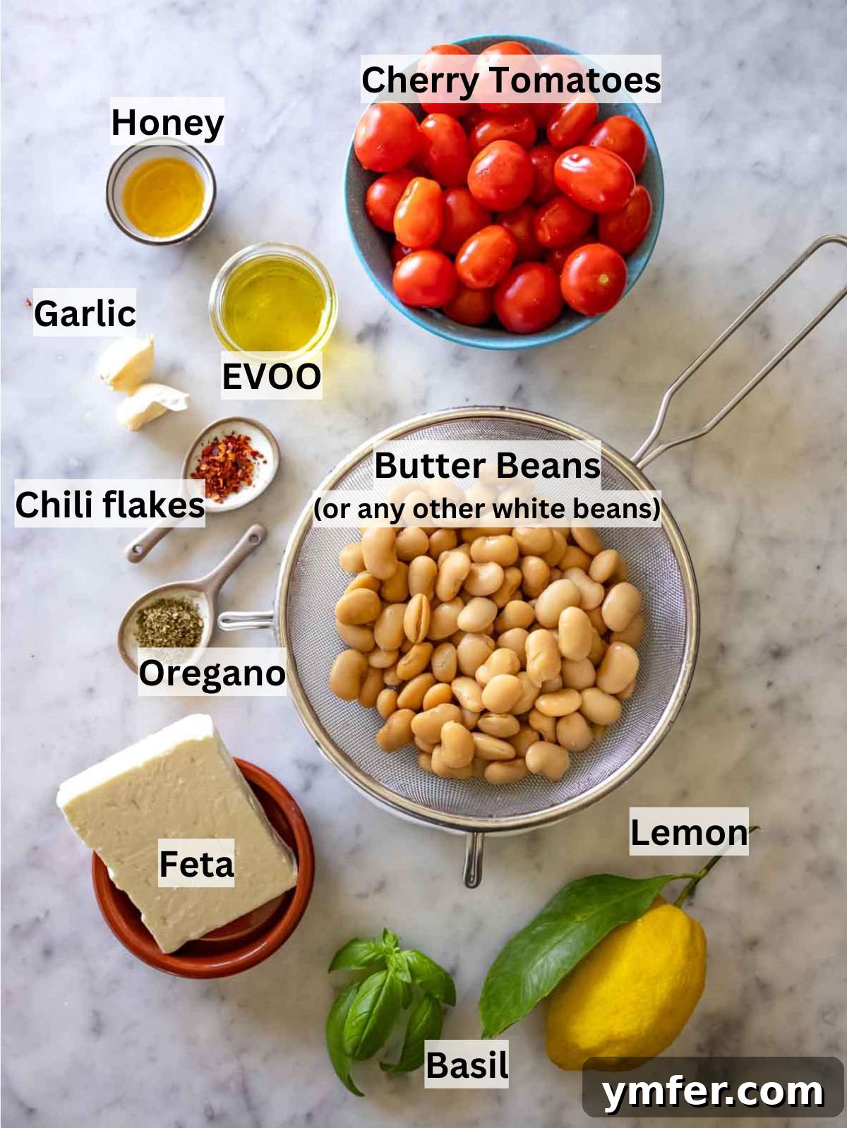 Creamy Butter Beans 4 All ingredients for butter bean recipe, including butter beans, tomatoes, feta, lemon, and fresh herbs, laid out on a rustic surface.