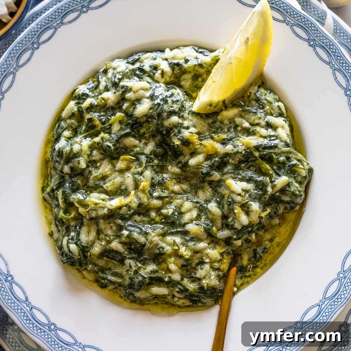 21 Greek Kitchen Classics 8 Traditional Spanakorizo (Greek spinach rice) served with a lemon wedge on a decorative Greek plate.
