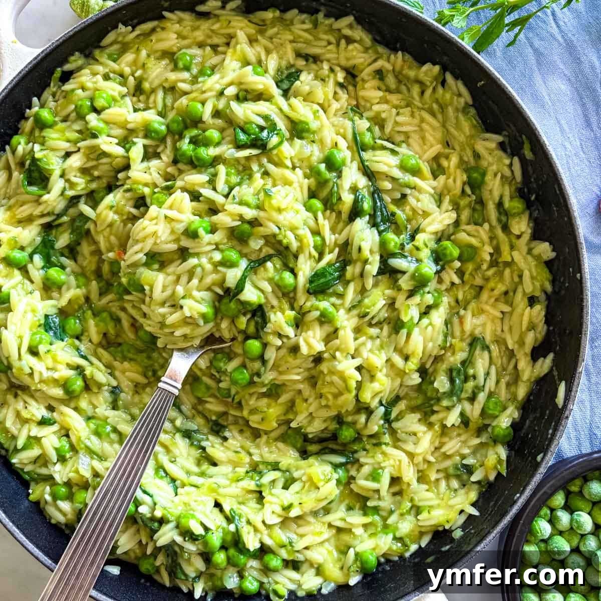 21 Greek Kitchen Classics 9 Close-up of creamy orzo with lemon and peas in a skillet, ready to be served.