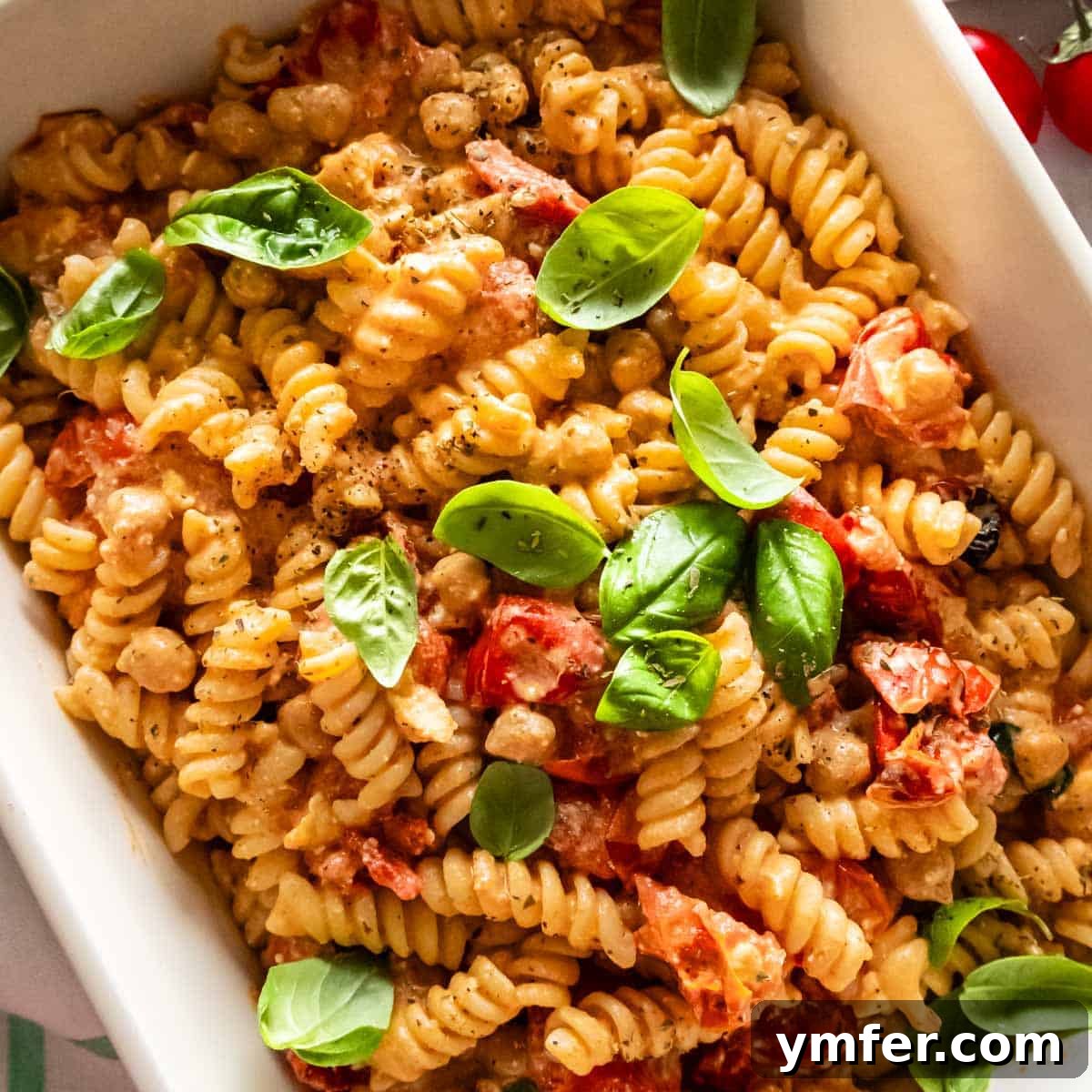 21 Greek Kitchen Classics 14 A vibrant pan of feta pasta recipe with cherry tomatoes, basil, and melted feta cheese.