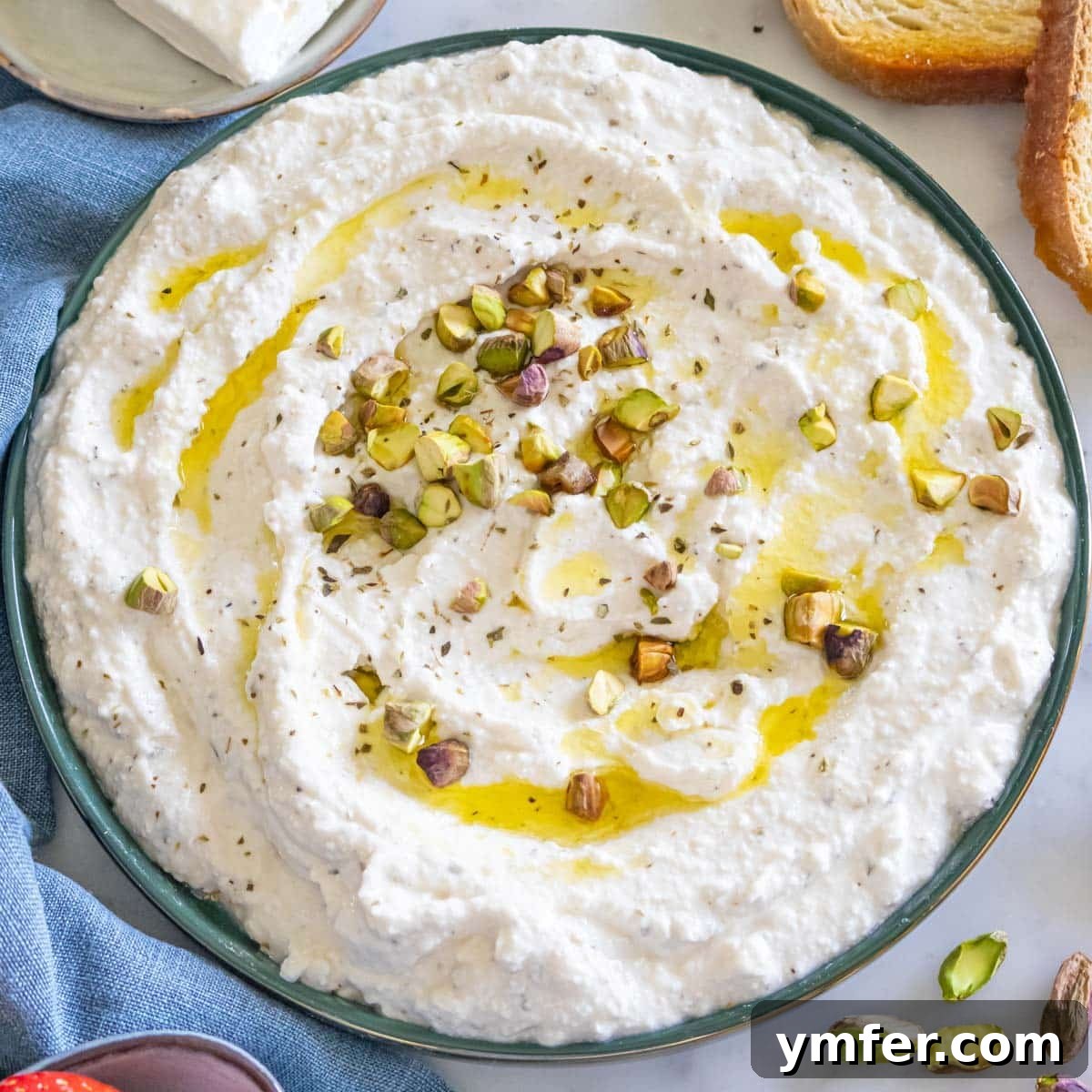 21 Greek Kitchen Classics 7 Smooth and creamy whipped feta dip in a serving bowl, garnished with fresh herbs.