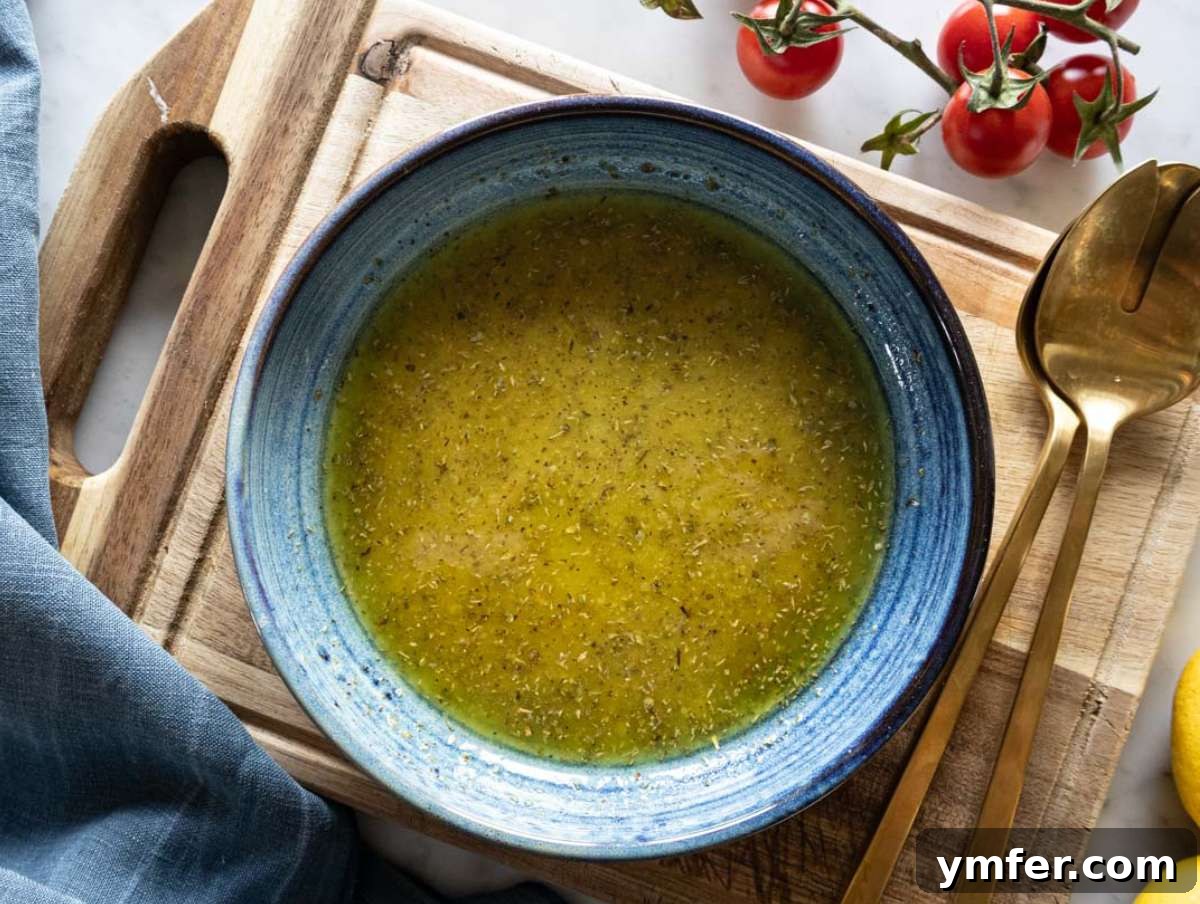 Vibrant Mediterranean Bowl 5 Step 2 - A close-up shot of hands whisking the lemon oregano dressing in a bowl, showing the vibrant color and texture of the dressing for Mediterranean chopped salad.