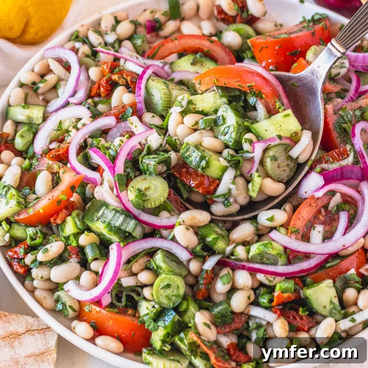 9 Mediterranean Proteins to Power Your Plate 11 A refreshing white bean salad featuring vine tomatoes and red onions, dressed with herbs, ready for serving.