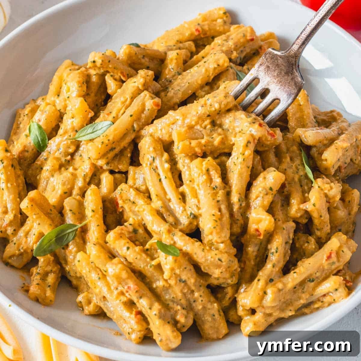 9 Mediterranean Proteins to Power Your Plate 18 Creamy tomato pasta, elegantly twirled with a fork and garnished with fresh basil leaves.