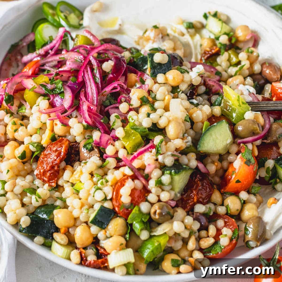 15 Effortless Pasta Salads You'll Crave All August 17 Israeli salad with sumac onions and pearl couscous on a white plate
