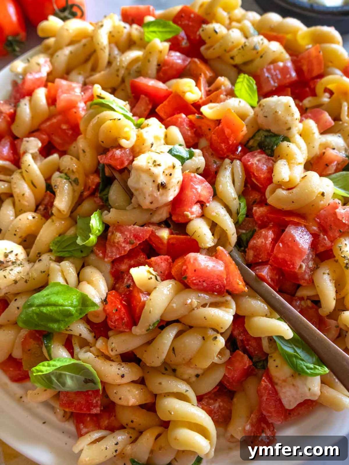 Easy Bruschetta Pasta No Cook Sauce 4 Bruschetta pasta close-up with melted mozzarella, fresh tomatoes, and basil on a white platter, ready to be enjoyed.