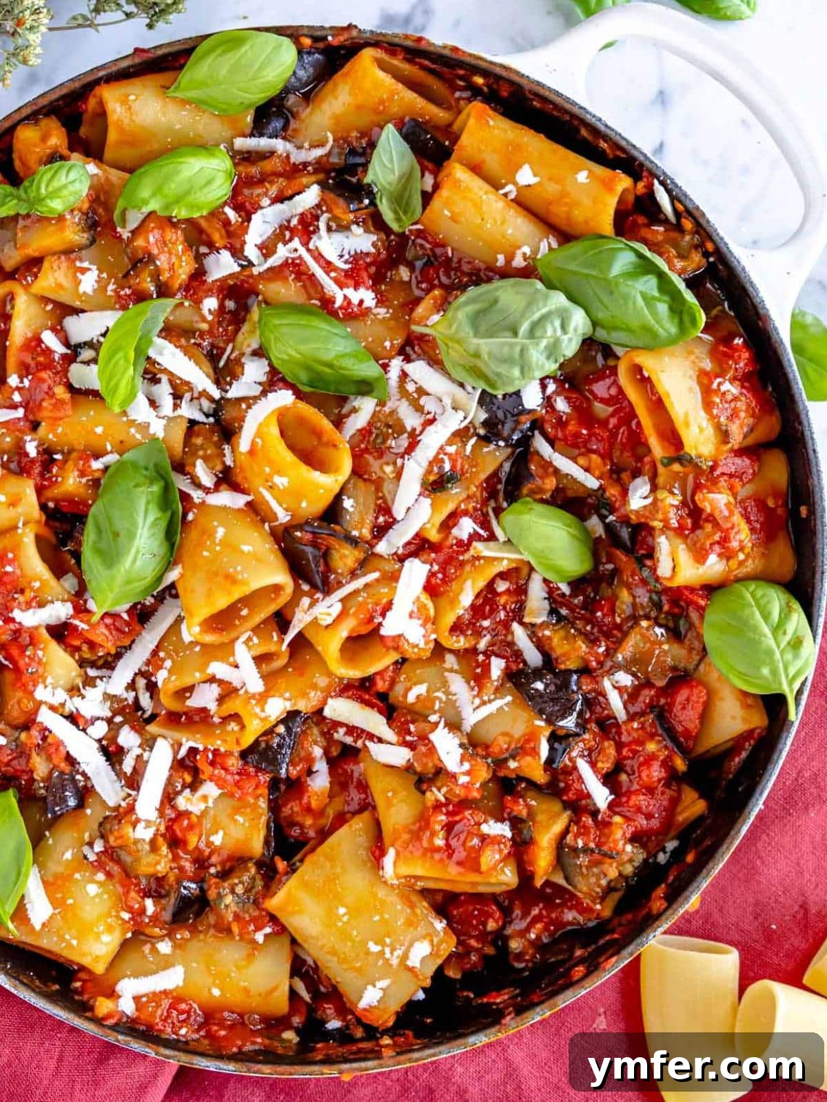 Top down view of pasta alla Norma in a skillet with ricotta salata.