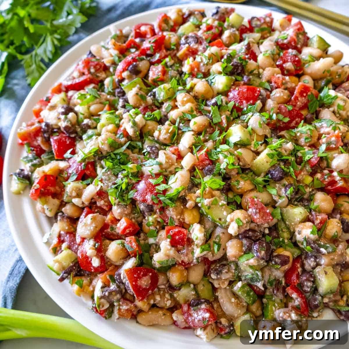 19 Simple Bean Recipes to Slash Your Weekly Food Bill 3 High protein bean salad in a large bowl with lemon wedges and parsley garnish, ready for a healthy meal.