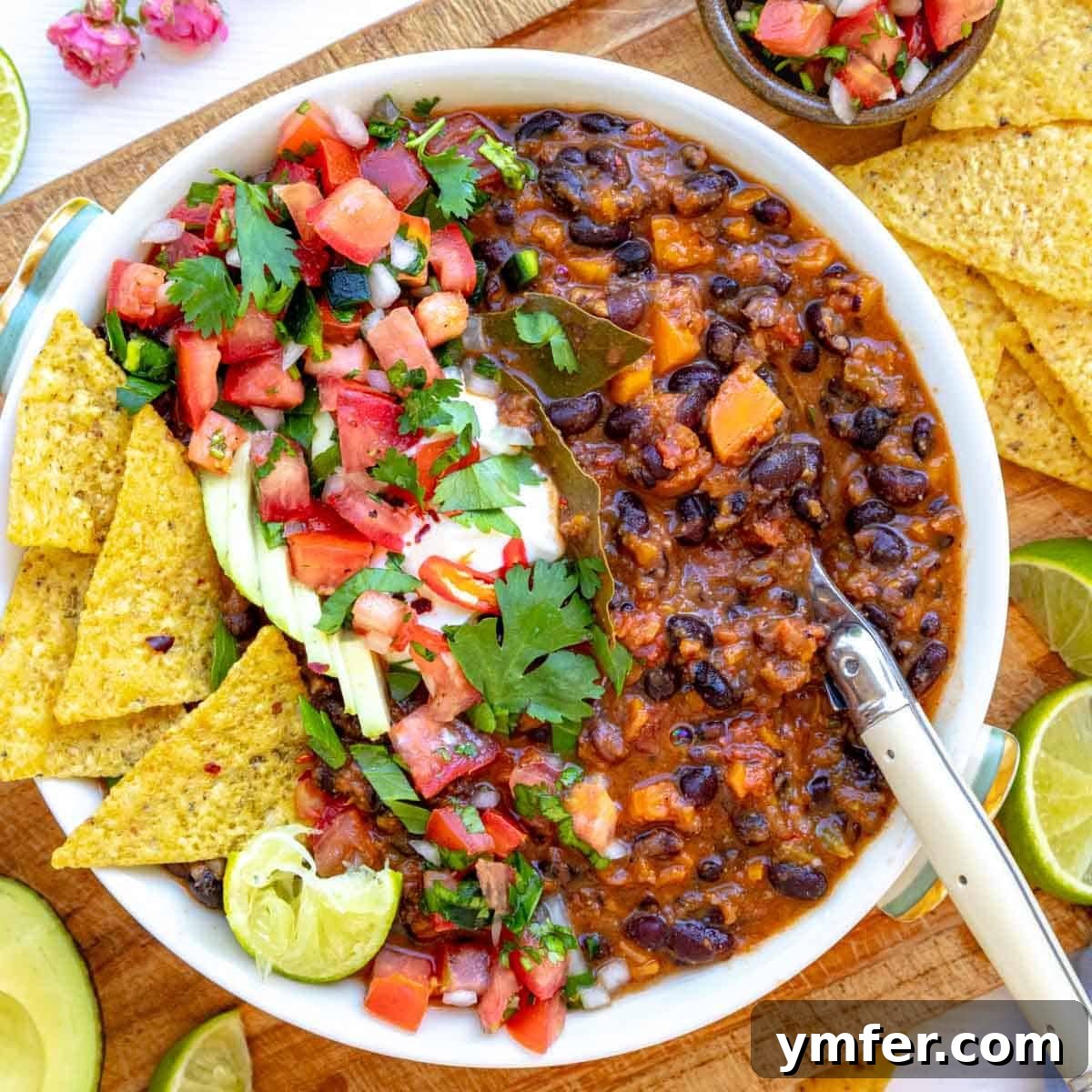 19 Simple Bean Recipes to Slash Your Weekly Food Bill 10 Black bean soup in a white bowl, garnished with fresh herbs and a swirl of cream, presented as a healthy and comforting soup meal.