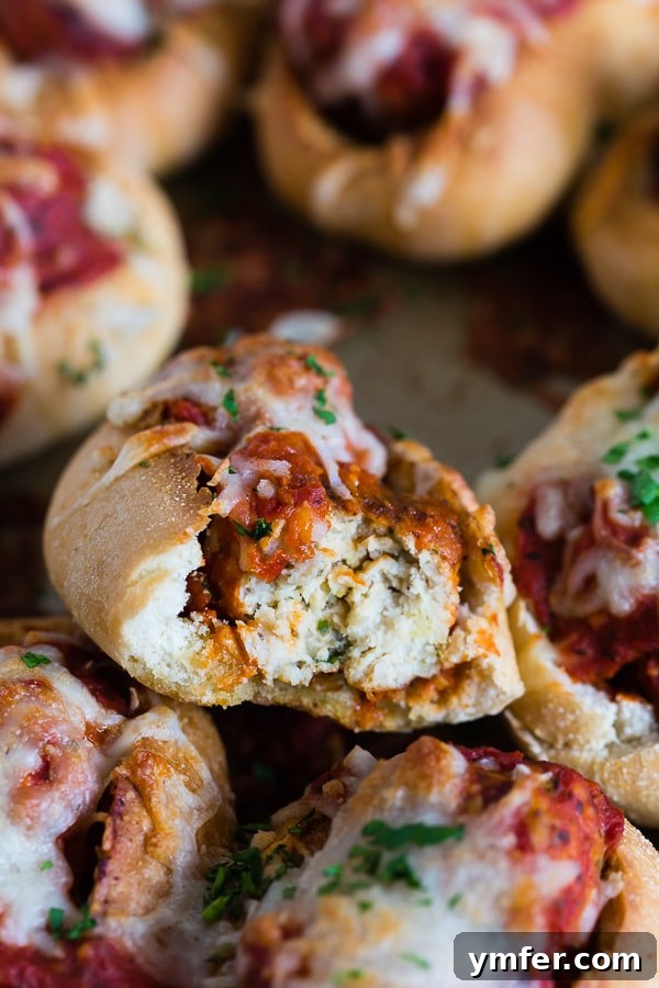 Cheesy Chicken Parm Meatball Sliders 4 A close-up shot of a Mini Chicken Parmesan Meatball Sub with a bite taken out, revealing the succulent chicken meatball, rich sauce, and perfectly melted cheese inside.
