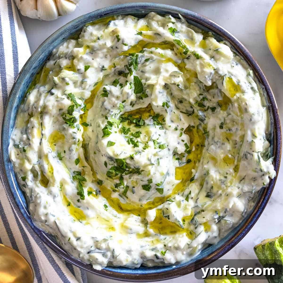 19 Brilliant Greek Yogurt Recipes for Lunch Dinner and Dessert 11 Fresh zucchini tzatziki dip in a bowl with olive oil and herb garnish, a classic Greek yogurt recipe.