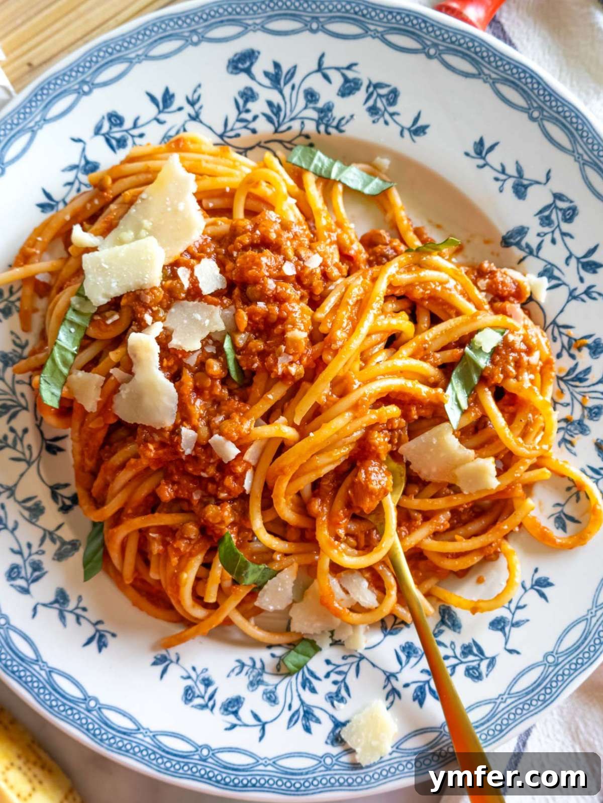 Speedy Lentil Bolognese Dinner in Half an Hour 2 Top down view of hearty lentil bolognese with spaghetti, garnished with fresh herbs.