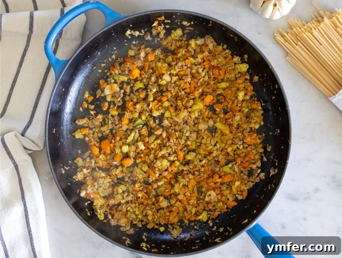 Speedy Lentil Bolognese Dinner in Half an Hour 5 Step 1: Sautéed vegetables, mushrooms, rosemary, salt, and pepper cooking in a skillet, creating an aromatic base.