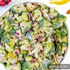 Fresh Mediterranean broccoli salad with yogurt dressing cranberries almonds and seeds on a table.