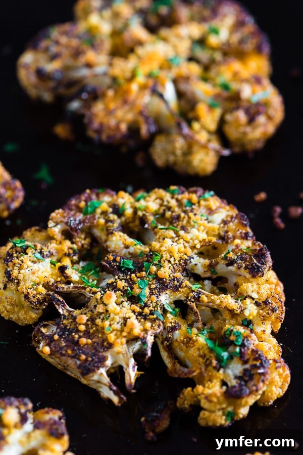 Golden Cajun Parmesan Cauliflower Steaks 3 Two perfectly cooked Parmesan Cajun Spiced Cauliflower Steaks, golden-brown and steaming on a baking pan, showing off their delicious crust.