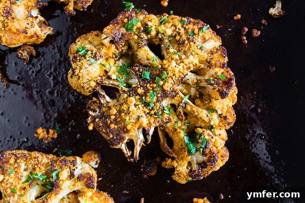 Golden Cajun Parmesan Cauliflower Steaks 5 A single Parmesan Cajun Spiced Cauliflower Steak beautifully presented on a black cooking pan, garnished with fresh parsley, highlighting its rich golden color and appealing texture.