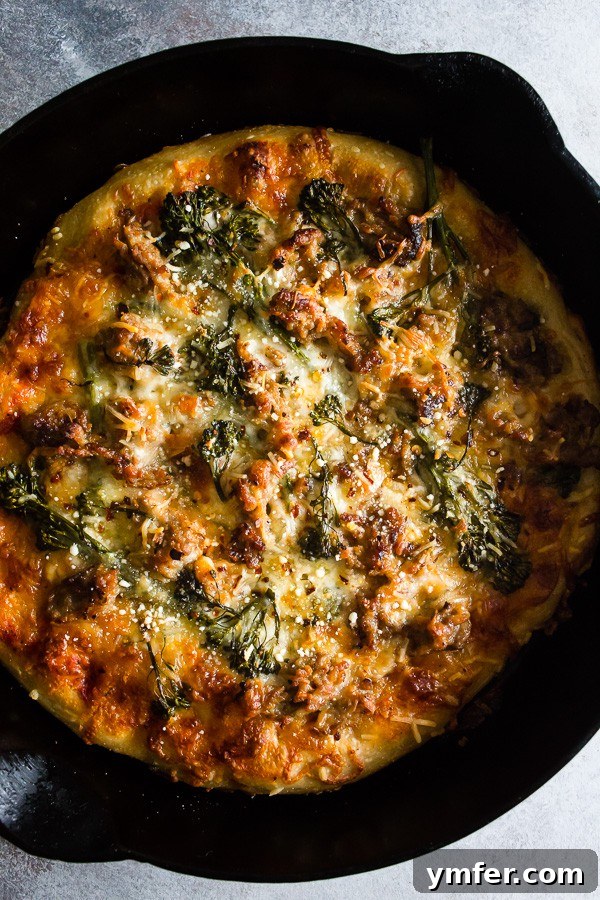 A vibrant Sausage Broccoli Rabe Skillet Pizza, freshly baked in a cast iron skillet, showcasing a golden-crisp crust, melted cheese, and tender broccoli rabe alongside crumbled Italian sausage.