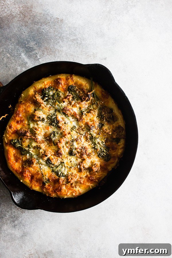 A close-up view of the Sausage Broccoli Rabe Skillet Pizza in a cast iron skillet, showcasing its rich toppings and crisp crust directly from the oven.